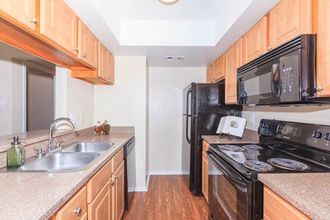 kitchen area with cabinets, refrigerator, microwave, range, dishwasher, sink
