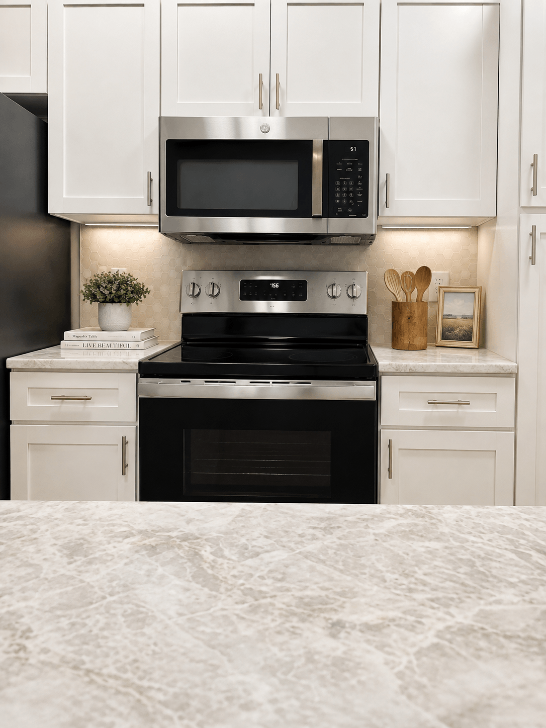Renovated apartment kitchen with stainless steel appliances, white shaker cabinets and stone counters