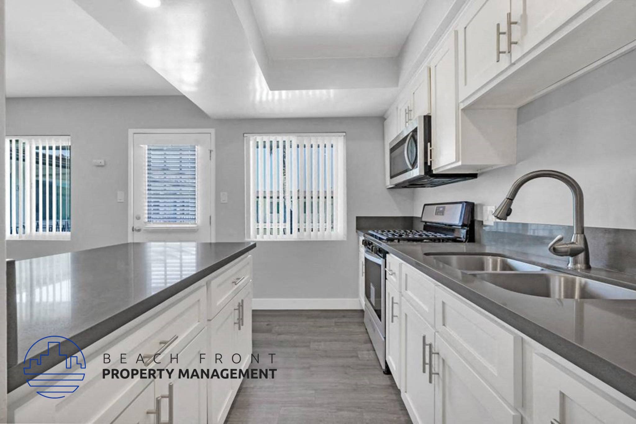 A kitchen with white cabinets and a stainless steel sink.