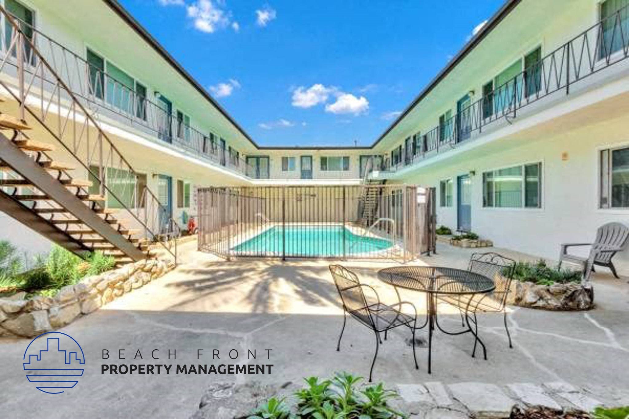 a courtyard with a pool and chairs and a table