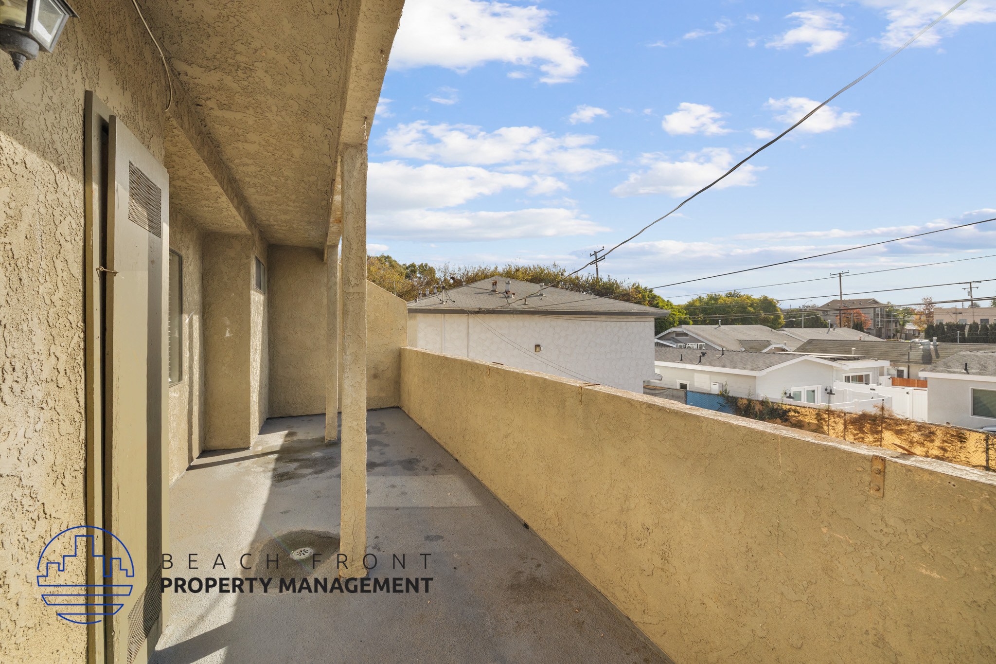 A balcony with a view of the neighborhood and a clear sky.