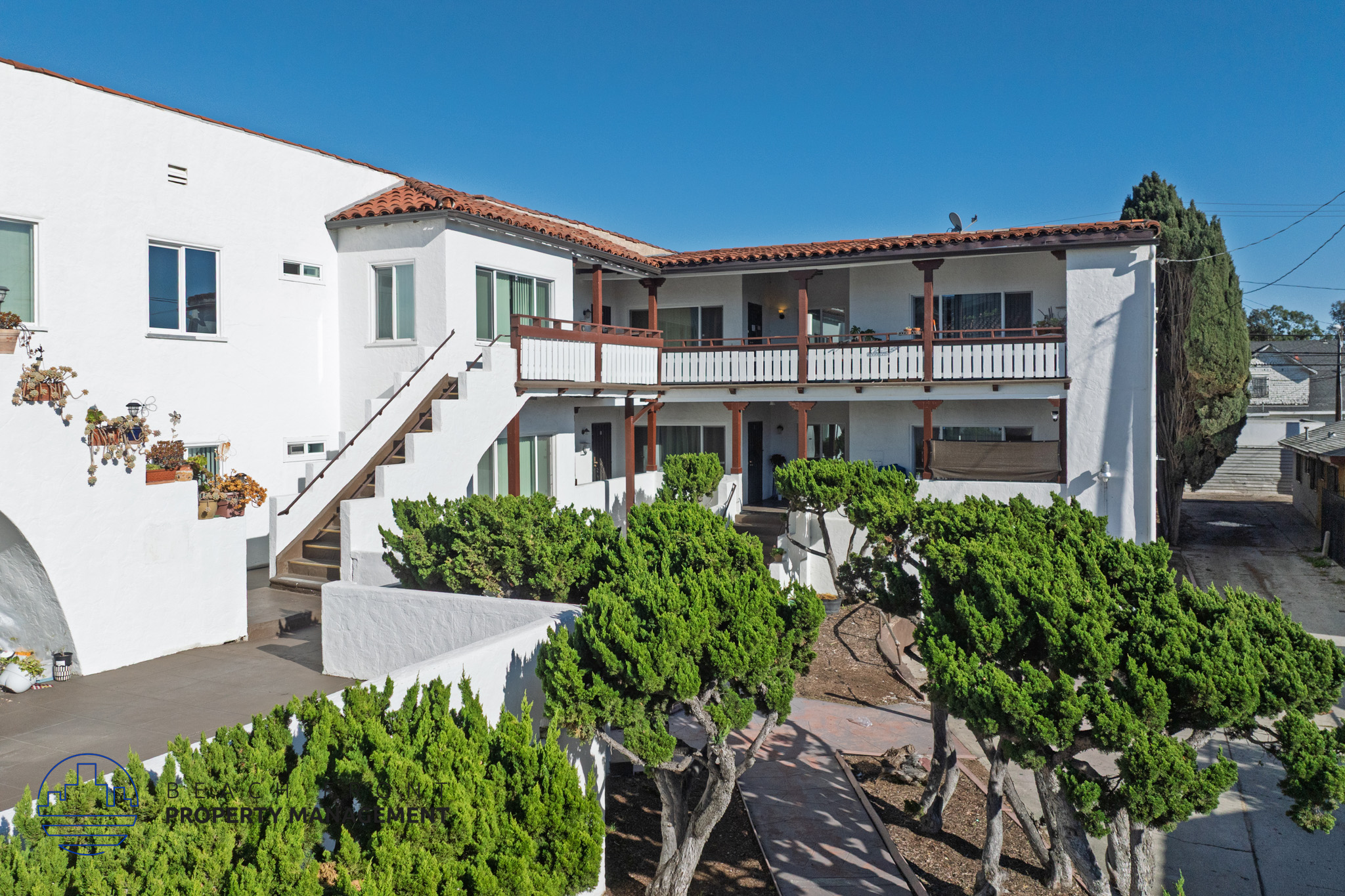 A white building with a red tile roof and a balcony.