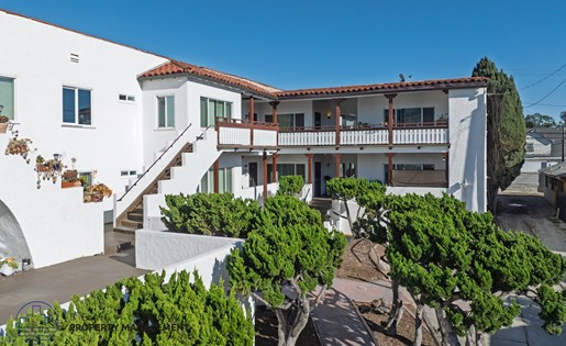 A white building with a red tile roof and a balcony.