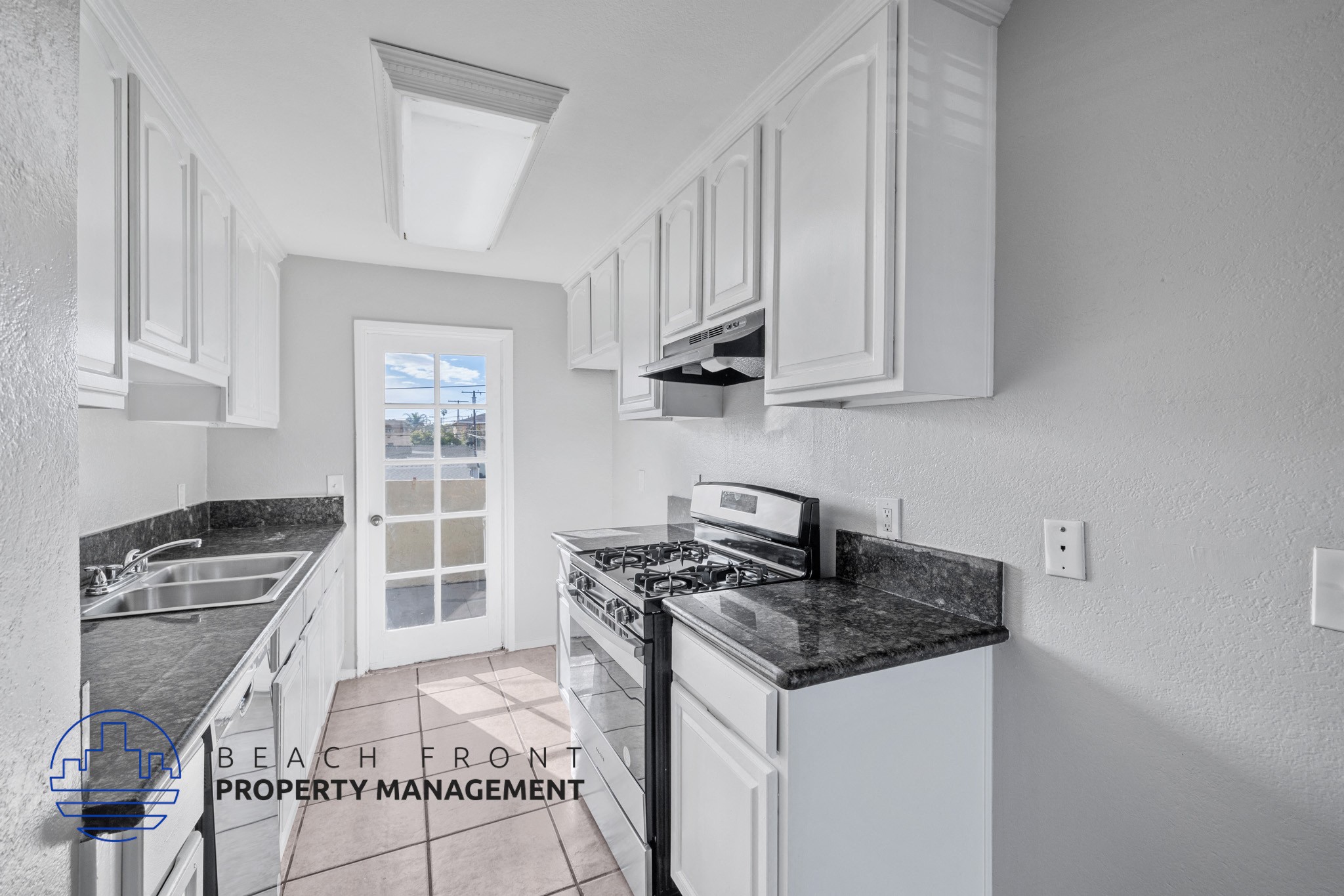 A kitchen with white cabinets and a black countertop.