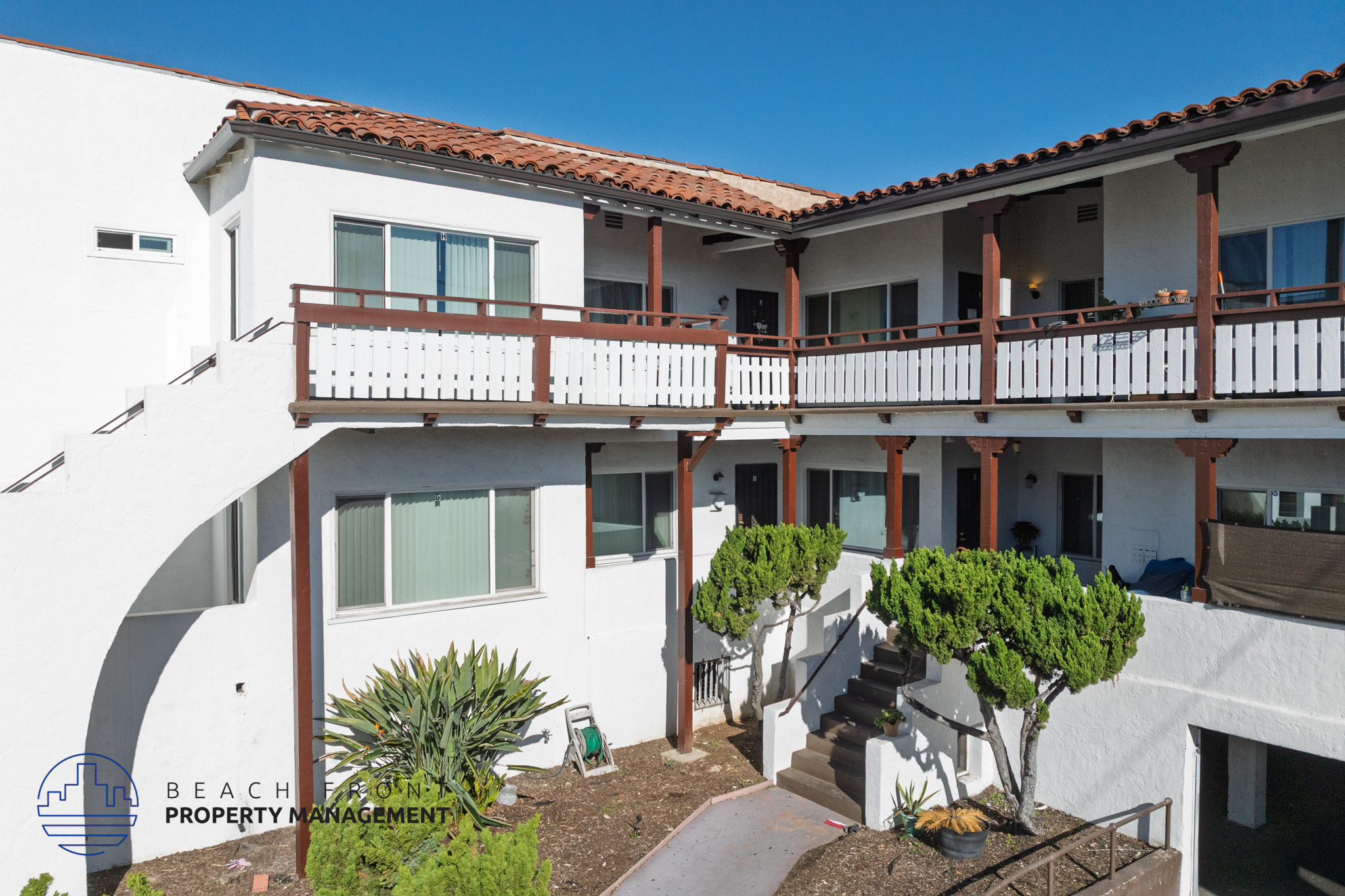 A white building with a red tile roof and a balcony.