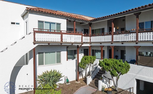 A white building with a red tile roof and a balcony.