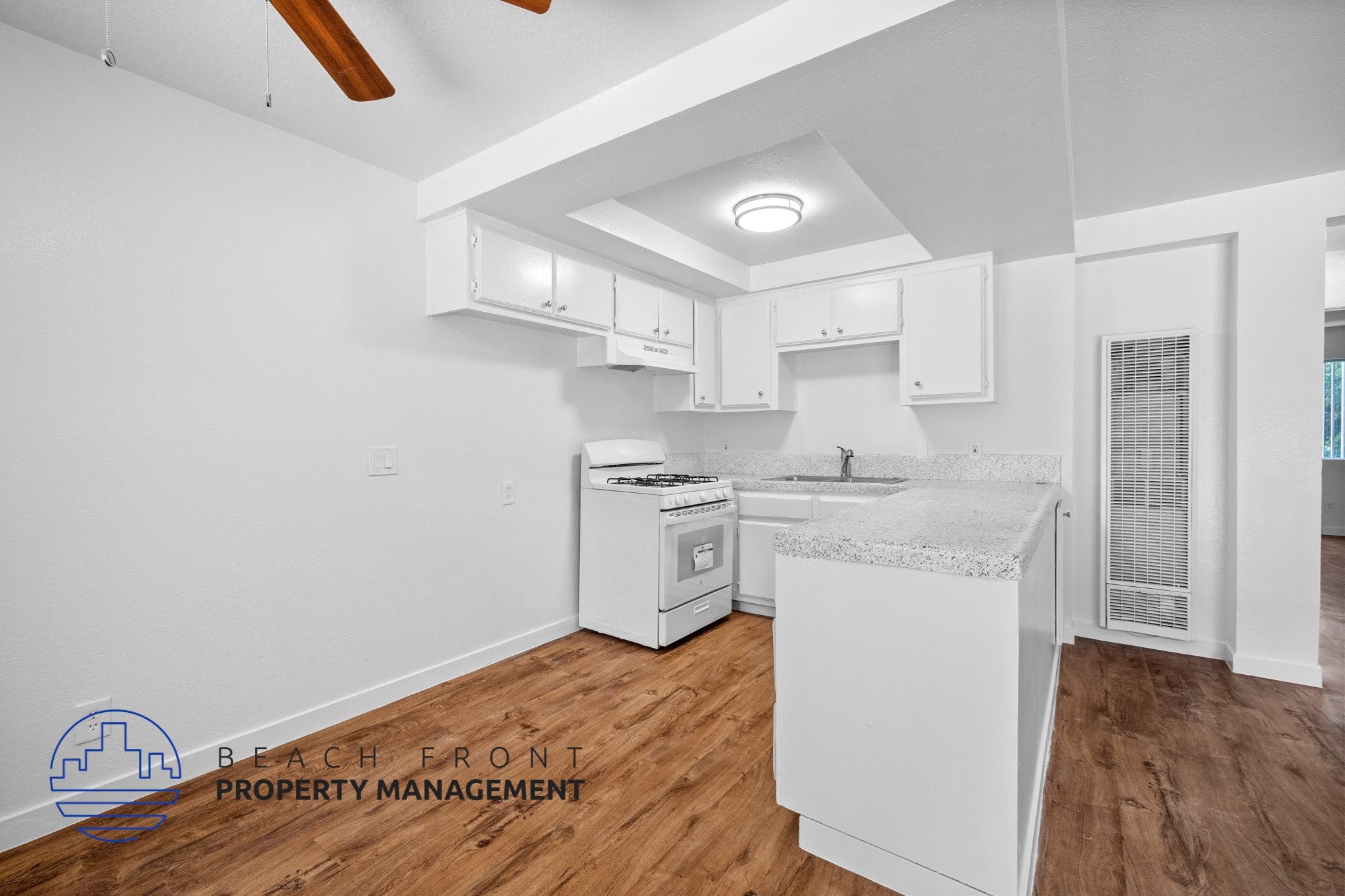 A kitchen with white cabinets and a wooden floor.,A kitchen with white cabinets and a wooden floor.