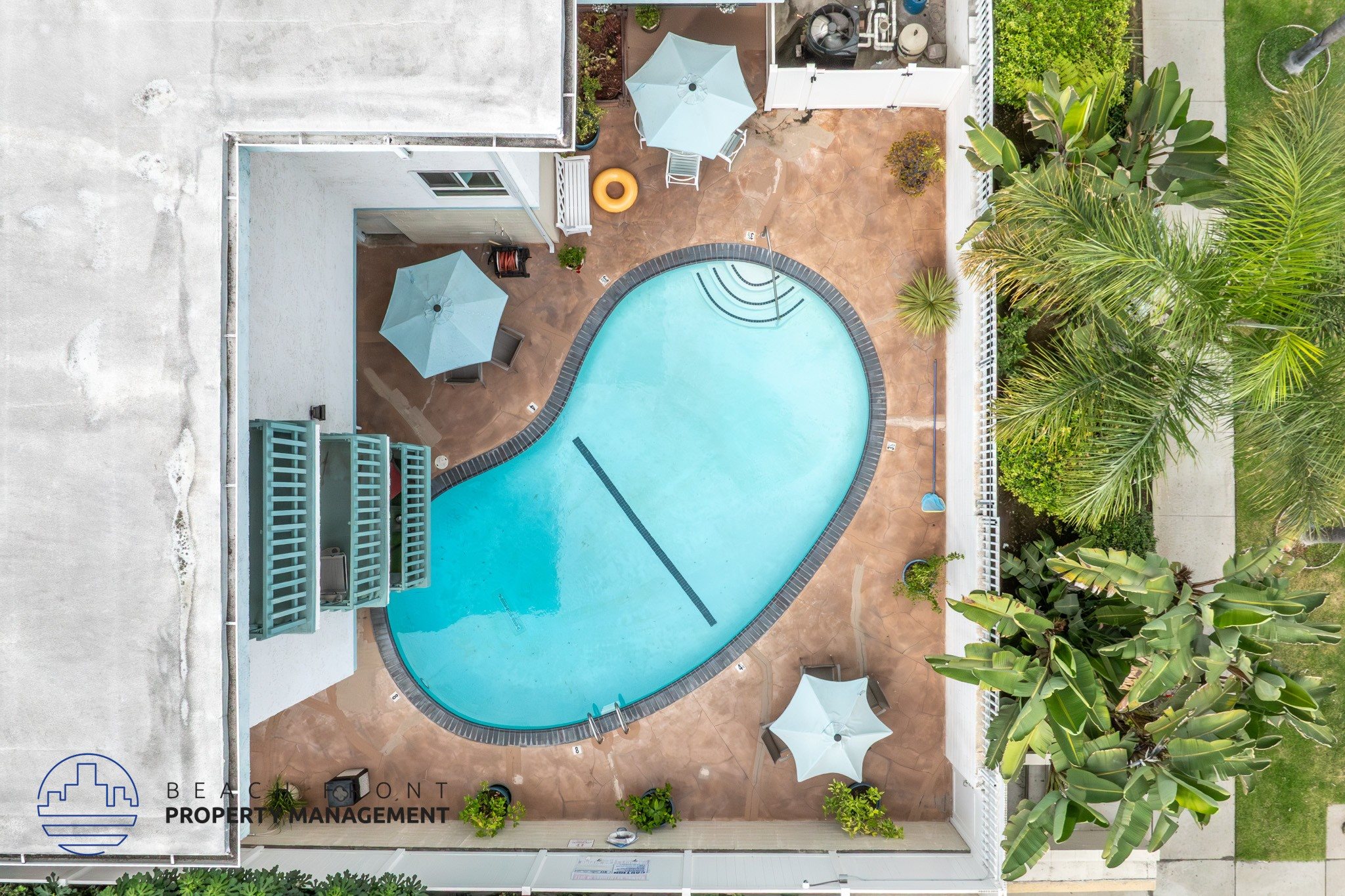 An aerial view of a pool surrounded by buildings and greenery.