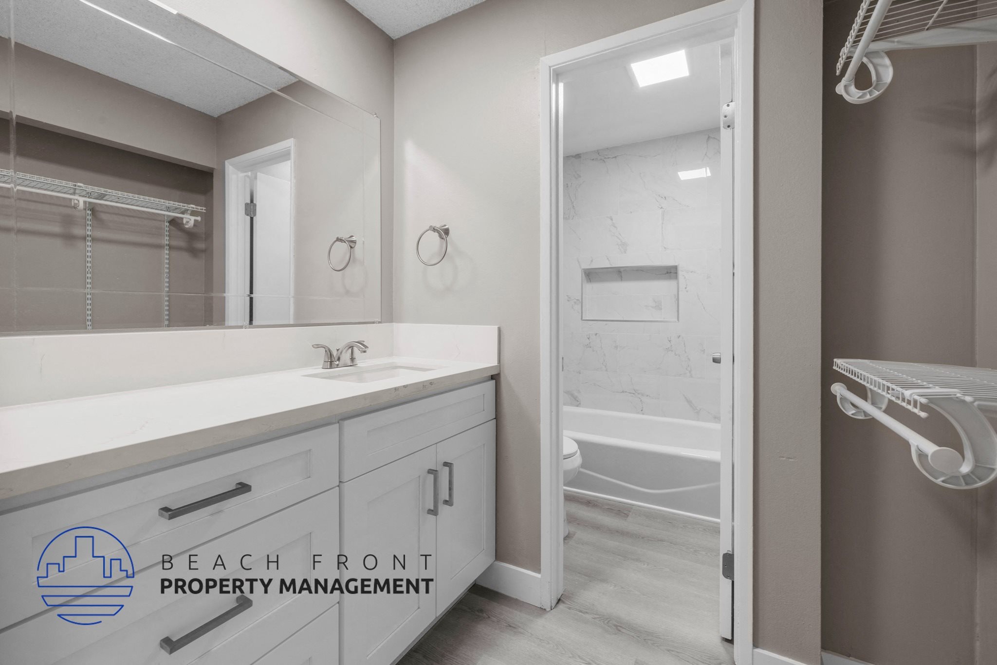 A bathroom with a sink, mirror, and a logo for Beach Front Property Management.