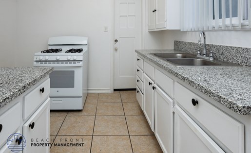 A kitchen with white cabinets and a granite countertop.