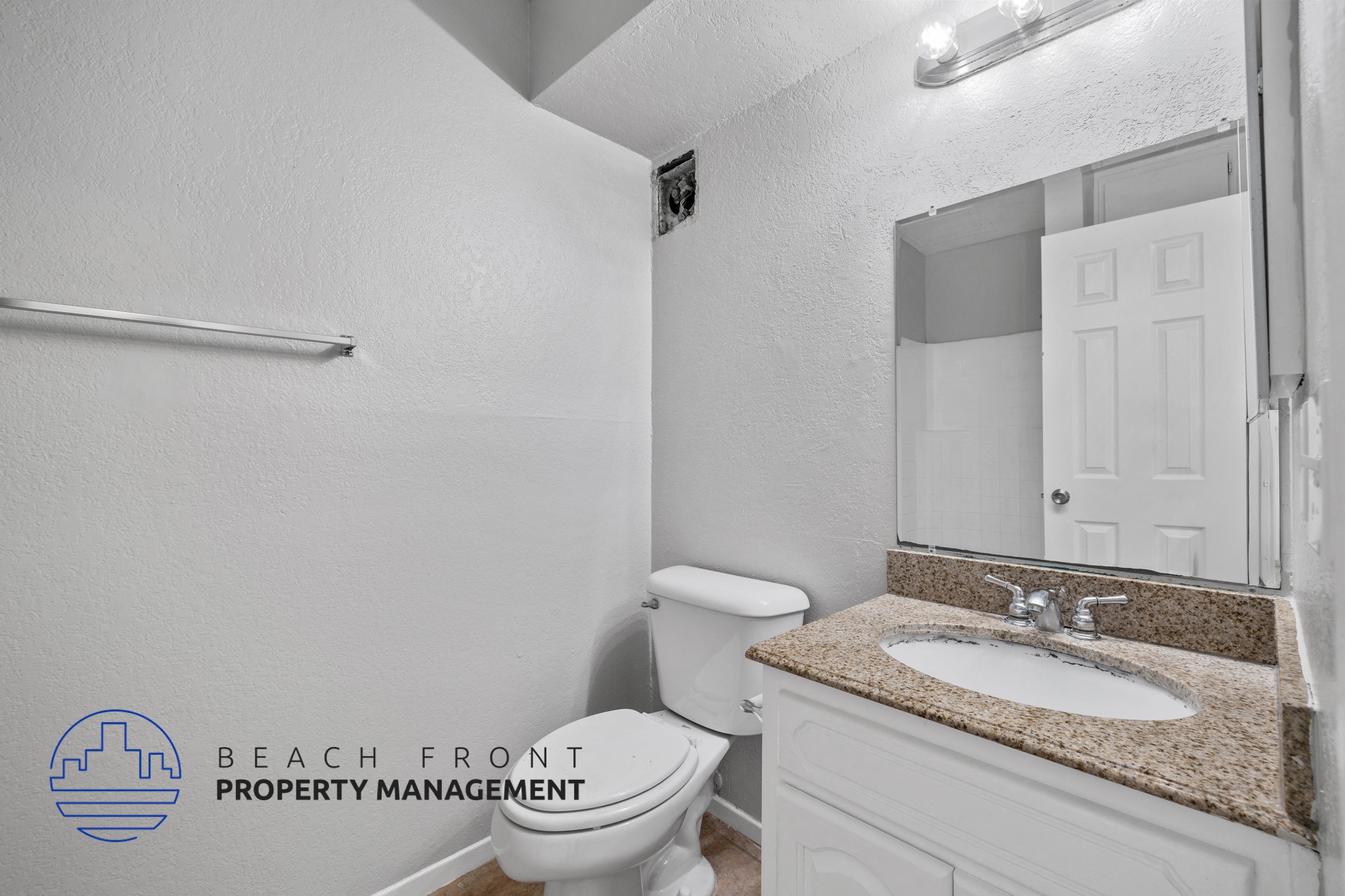 A bathroom with a toilet, sink, and mirror.