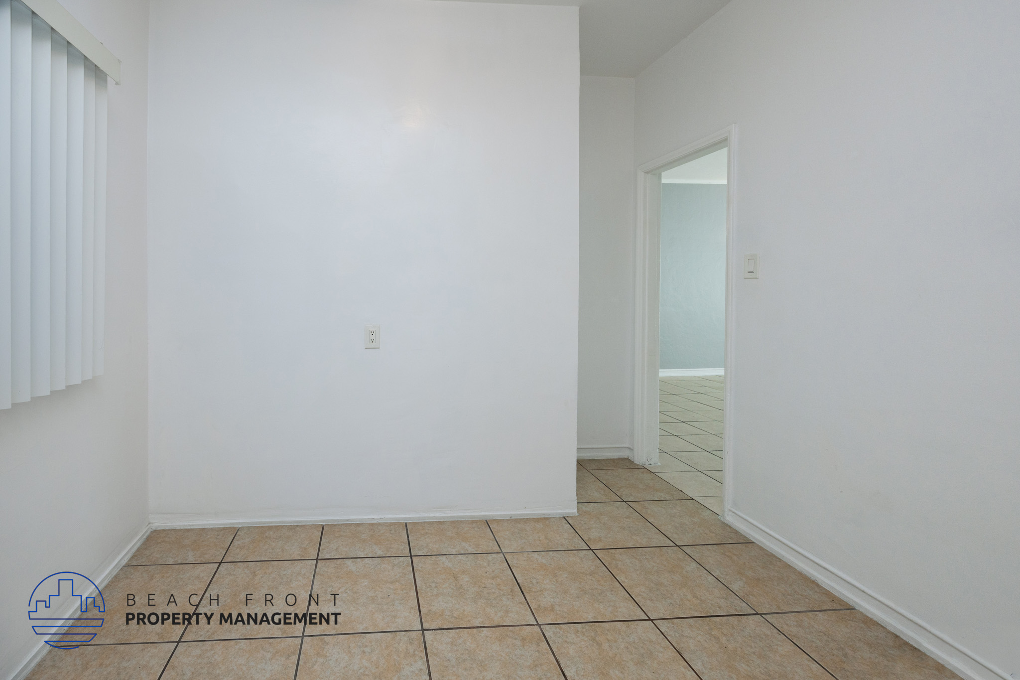 A room with white walls and tiled flooring with a logo for Beach Front Property Management.
