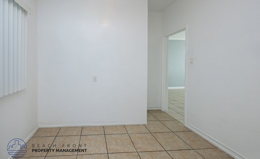 A room with white walls and tiled flooring with a logo for Beach Front Property Management.