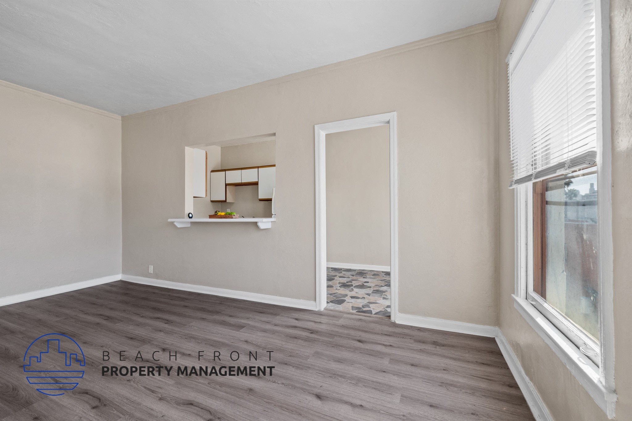 A room with a window and a shelf with a logo of Beach Front Property Management.