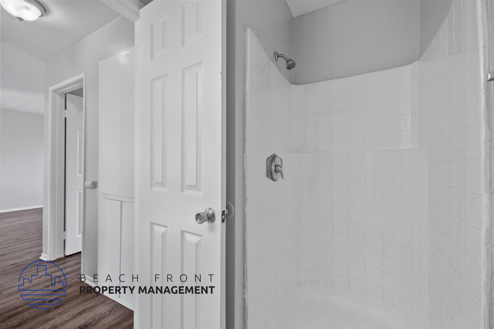 A white bathroom with a white door and a white shower.