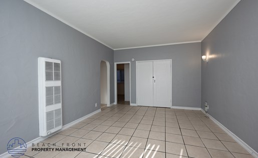A spacious room with tiled flooring and white doors and windows.