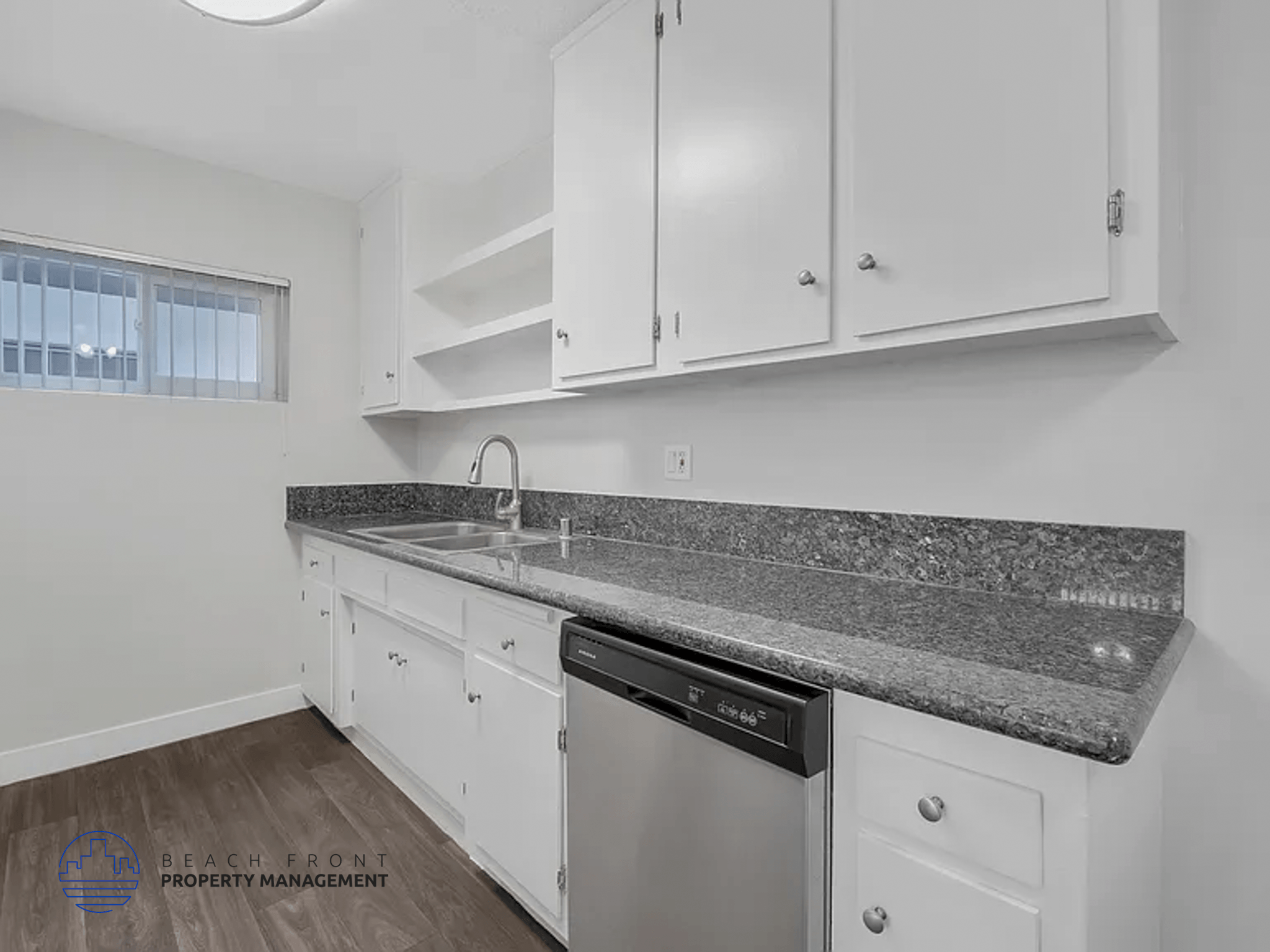 A kitchen with white cabinets and a granite countertop.