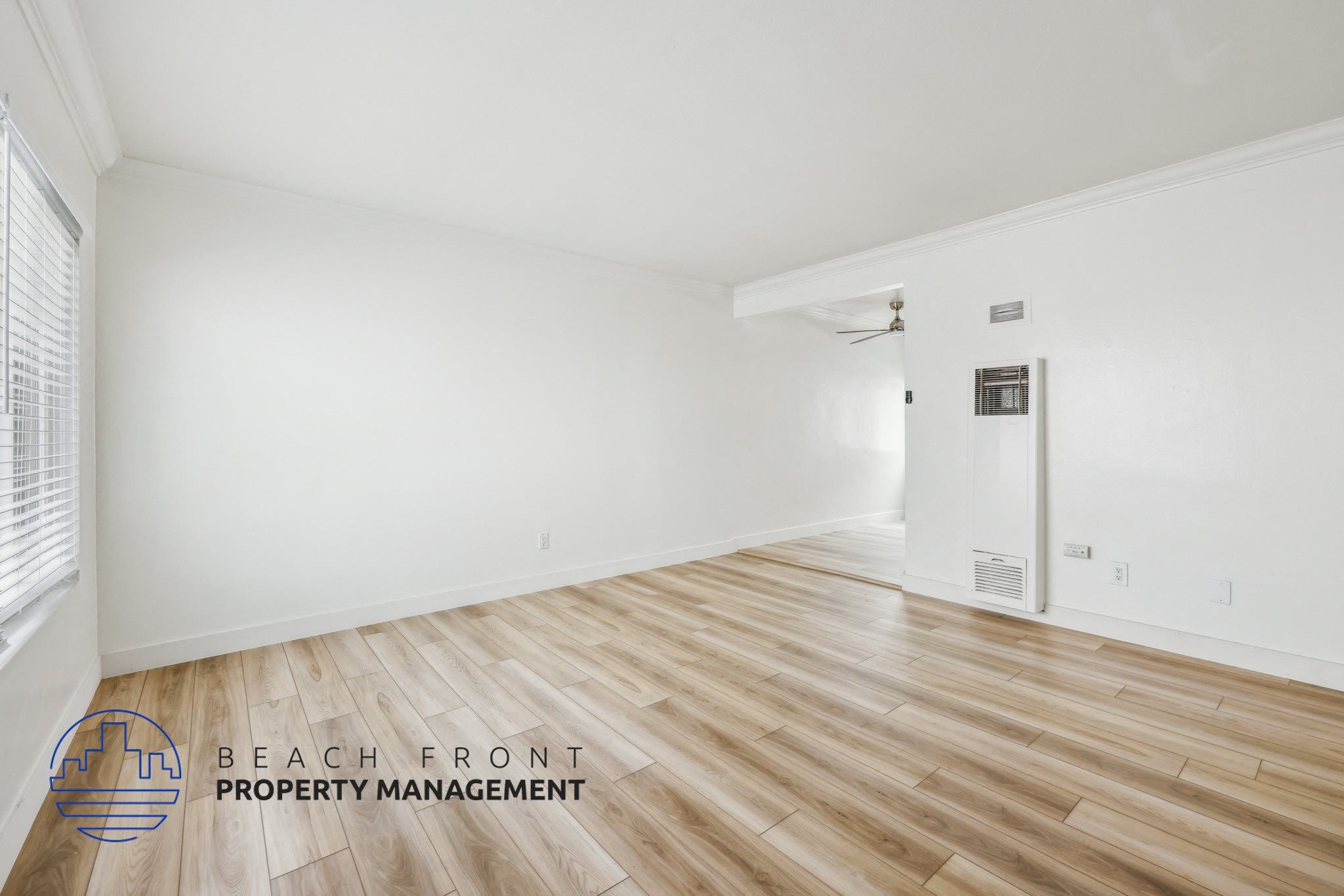 A room with wooden flooring and a logo for Beach Front Property Management.