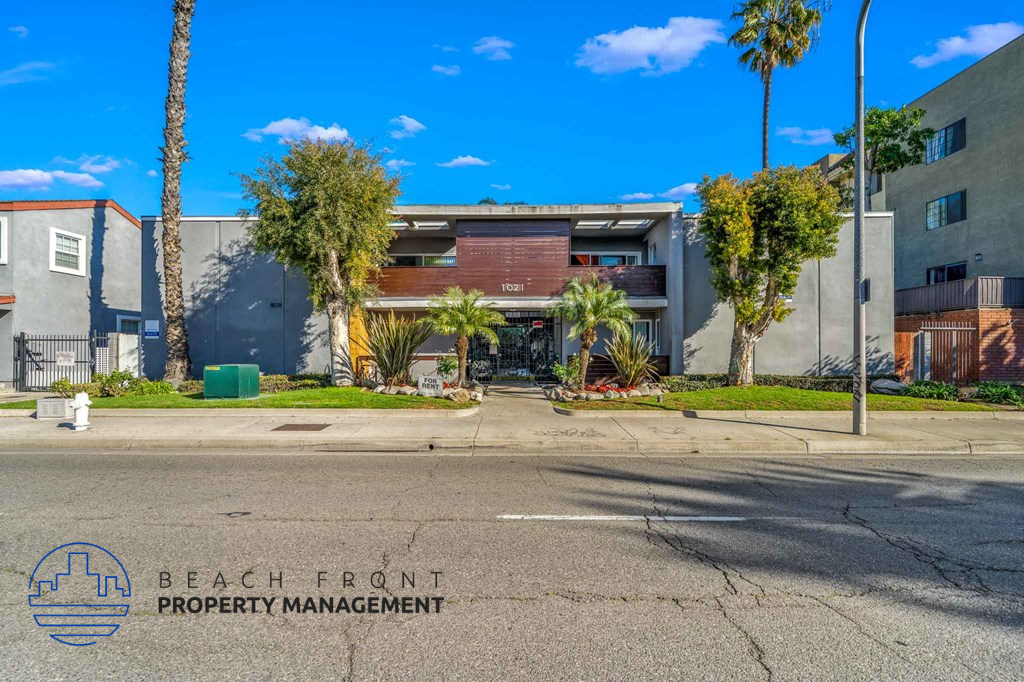 A street view with a building and palm trees in front of it.