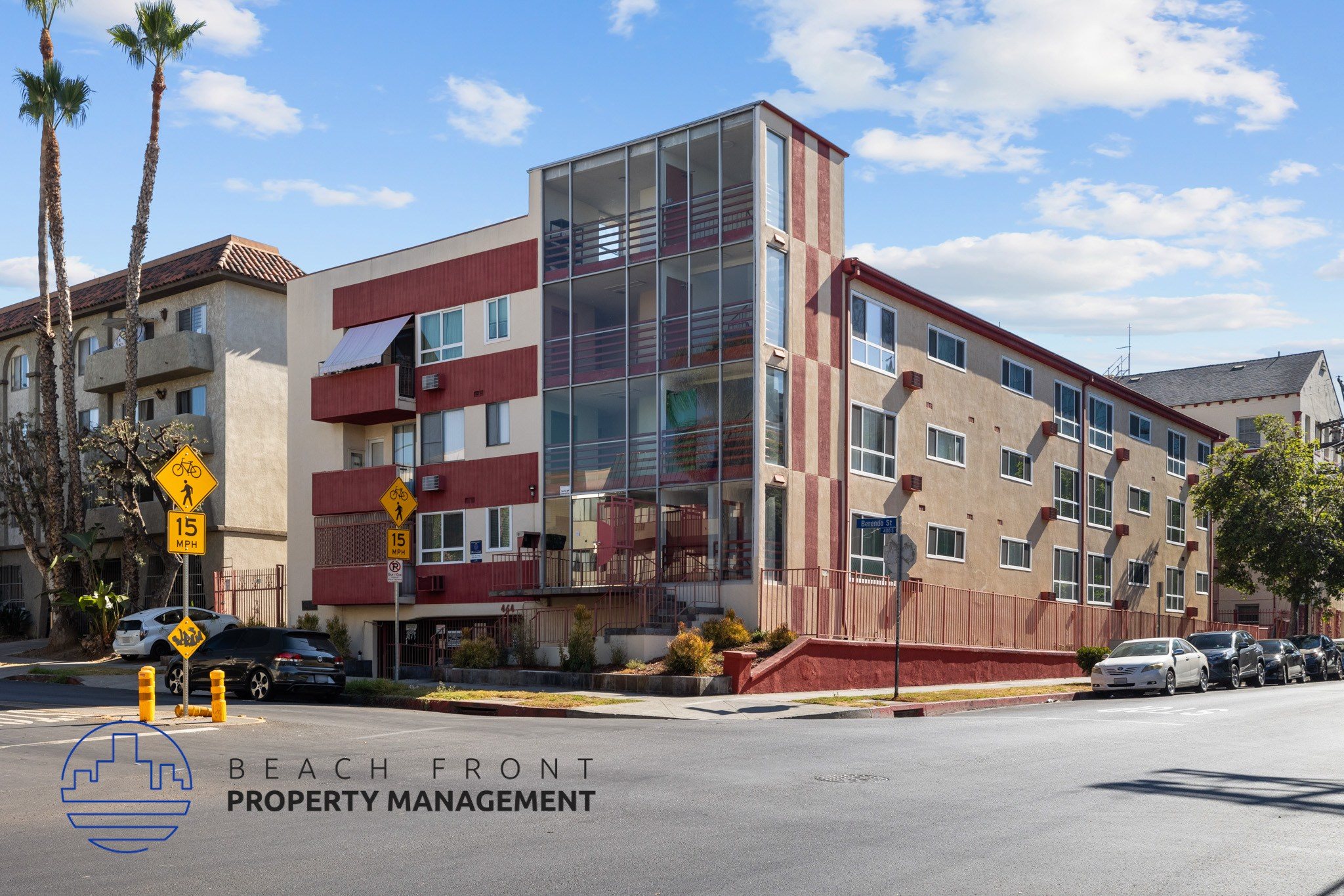A multi-story building with a red and beige facade is under construction with a sign that reads "BEACH FRONT PROPERTY MANAGEMENT".