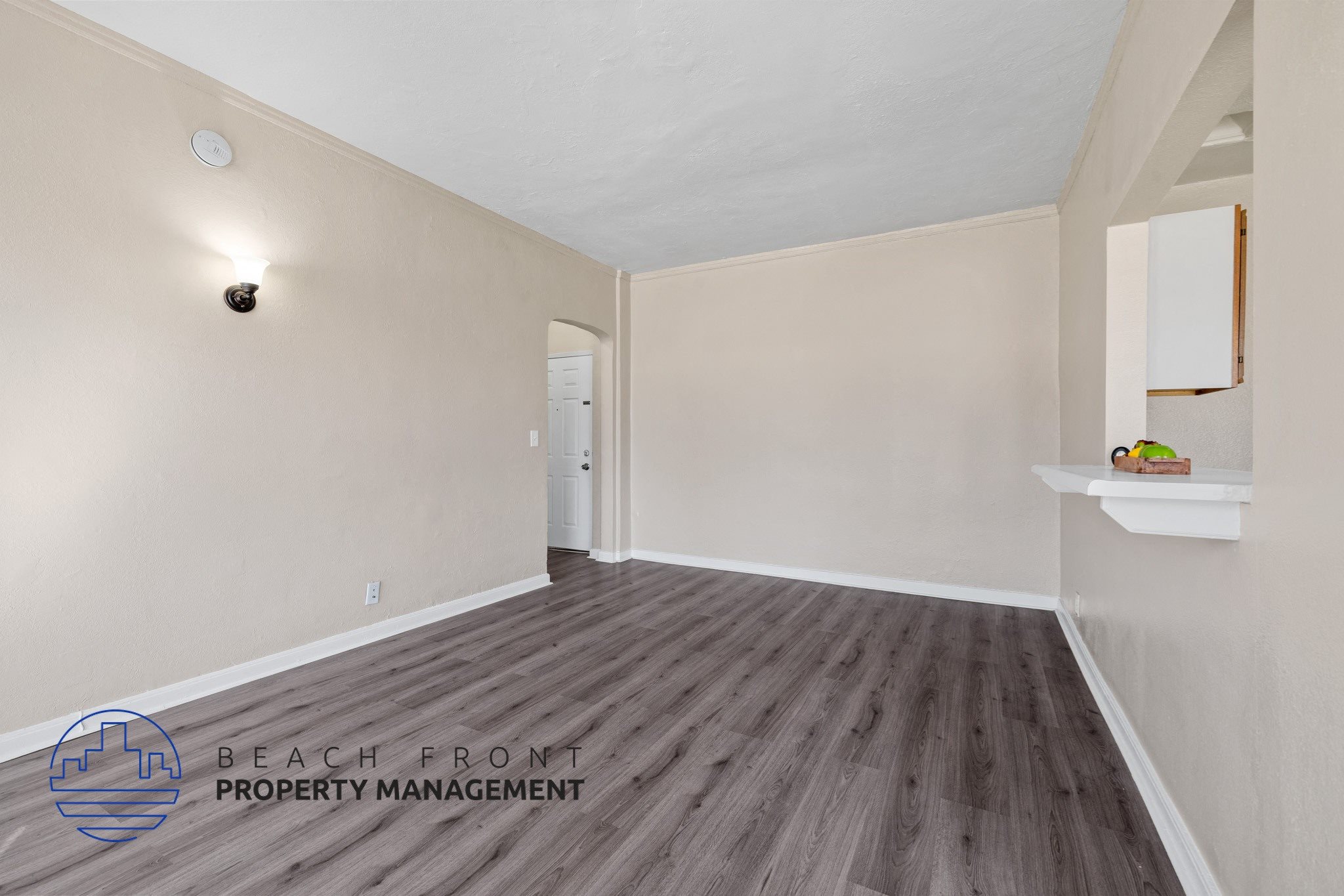 A room with wooden flooring and a logo for Beach Front Property Management.