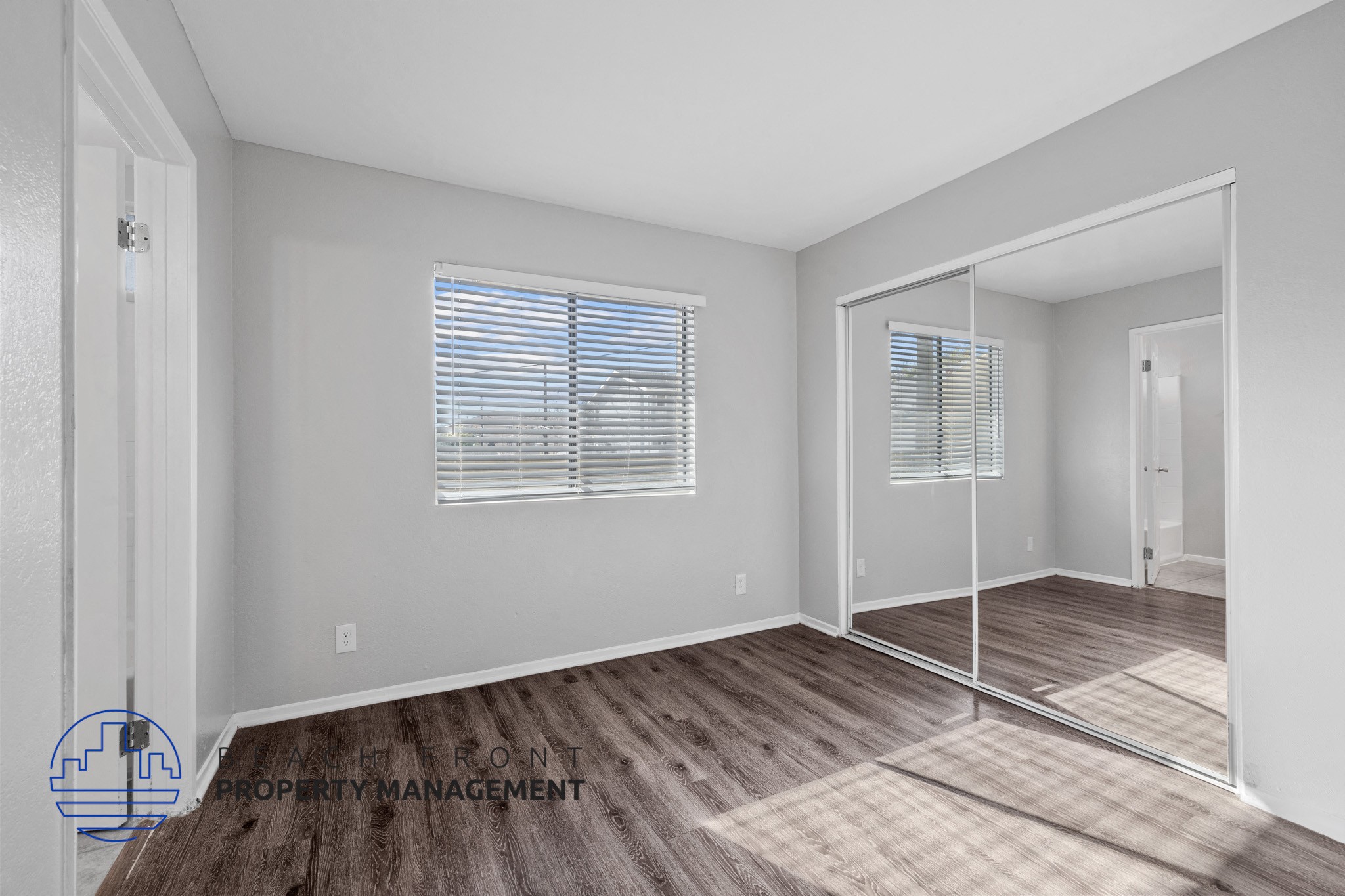 A room with a wooden floor and a large mirror on the wall.