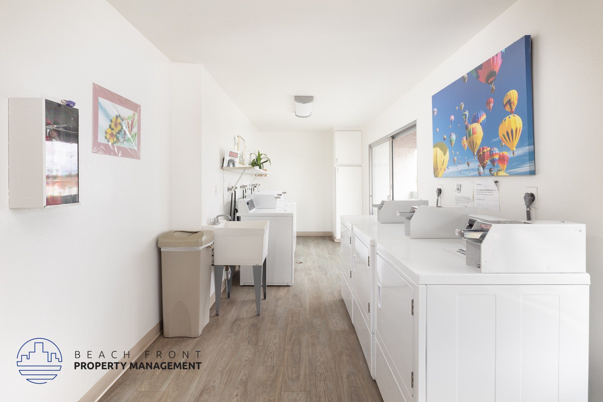 A clean, white-walled office space with a desk, chairs, and a large painting on the wall.