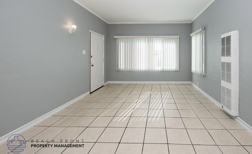 A spacious room with tiled flooring and a window with blinds.
