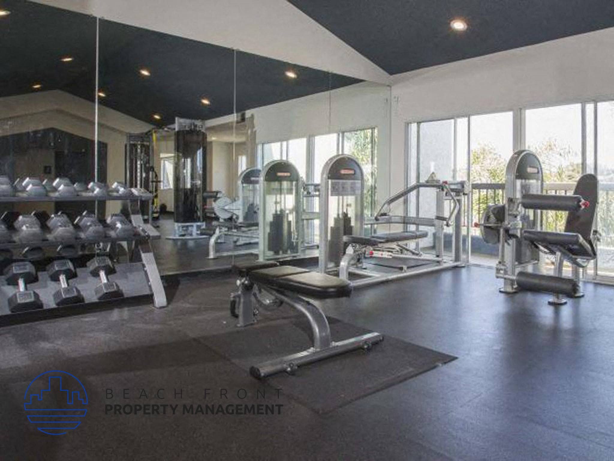 A gym with a variety of equipment including dumbbells, weight machines, and a bench press.