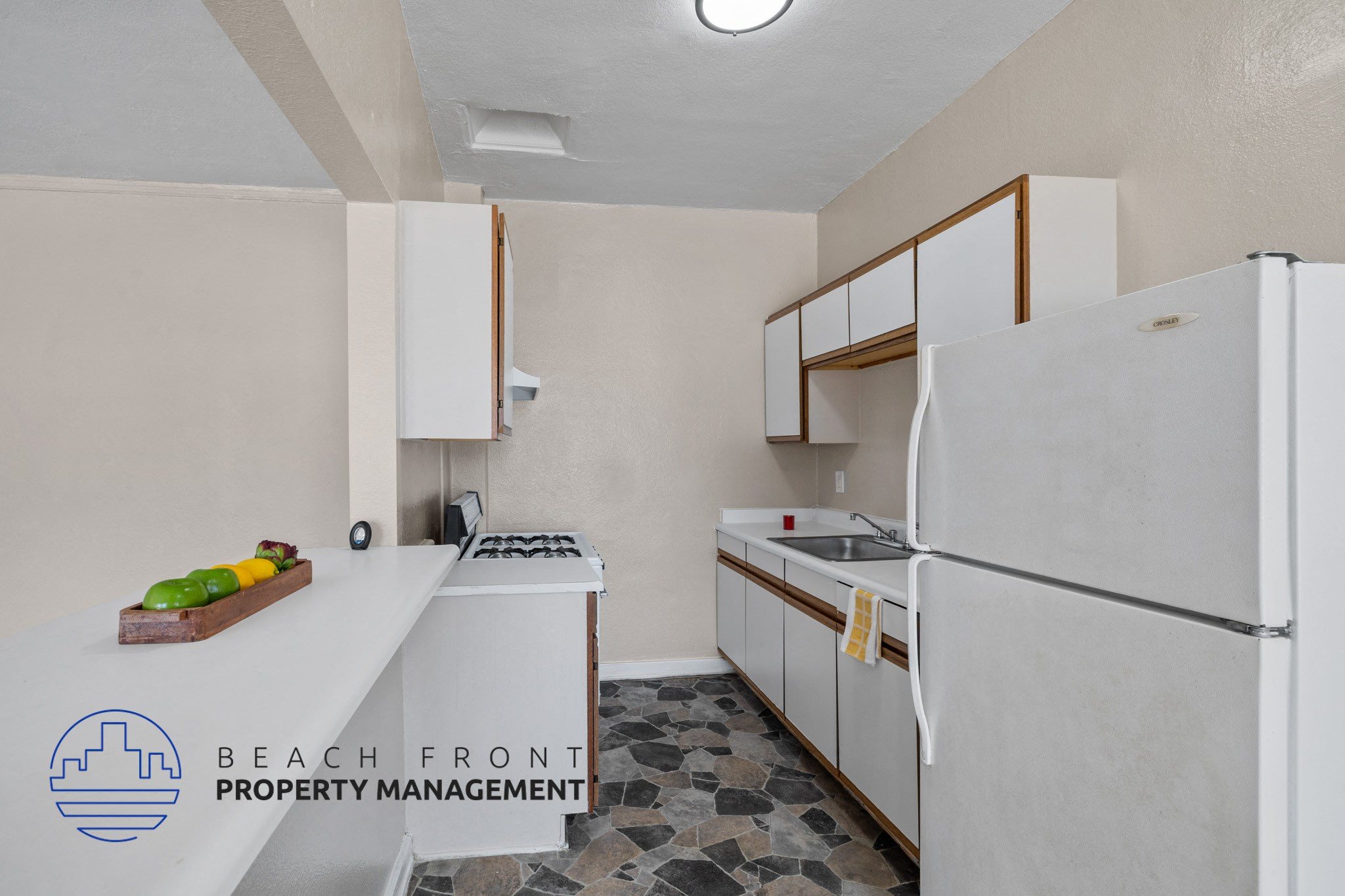 A kitchen with a refrigerator, sink, stove and cabinets.