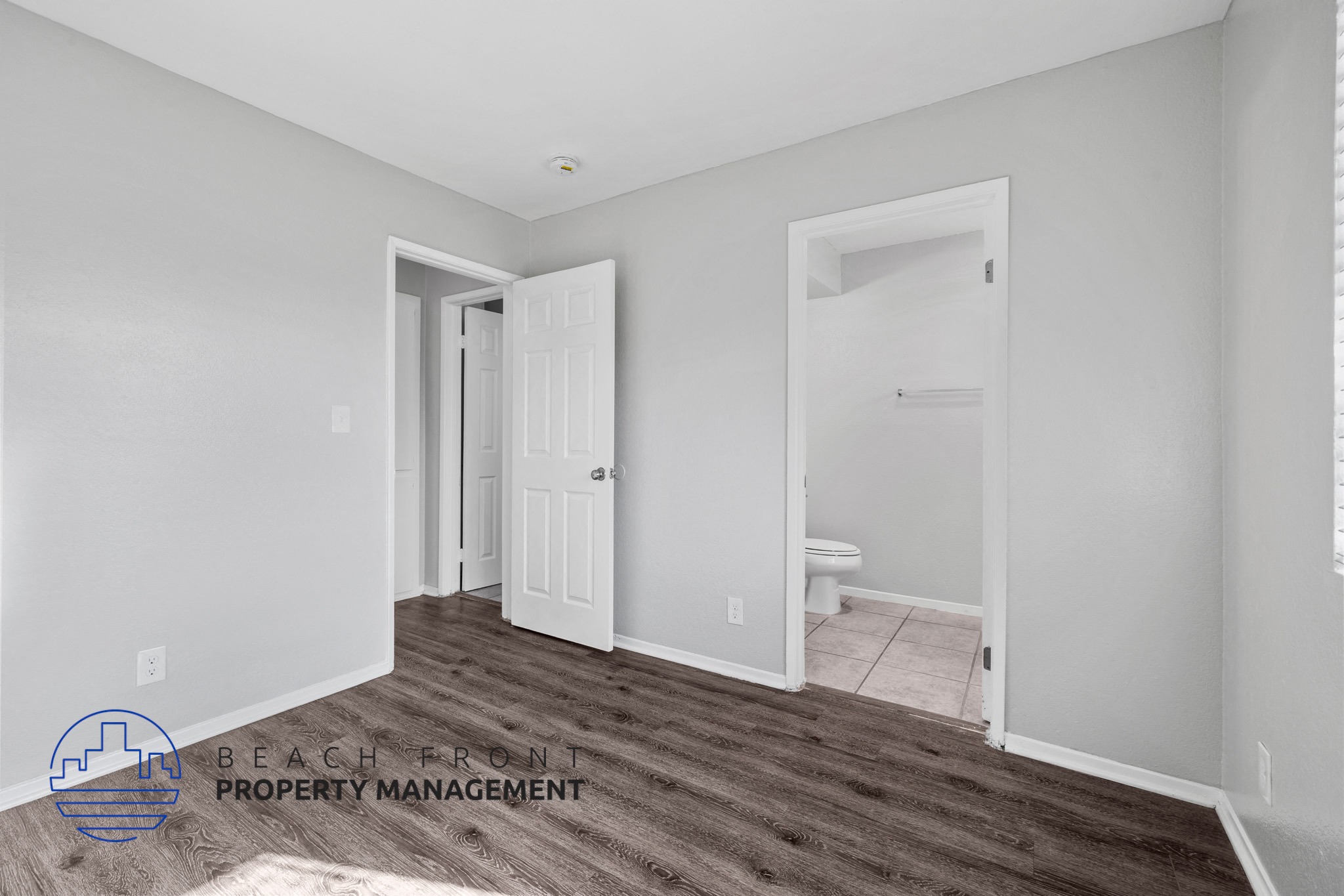 A room with a white door and a window on the right side.