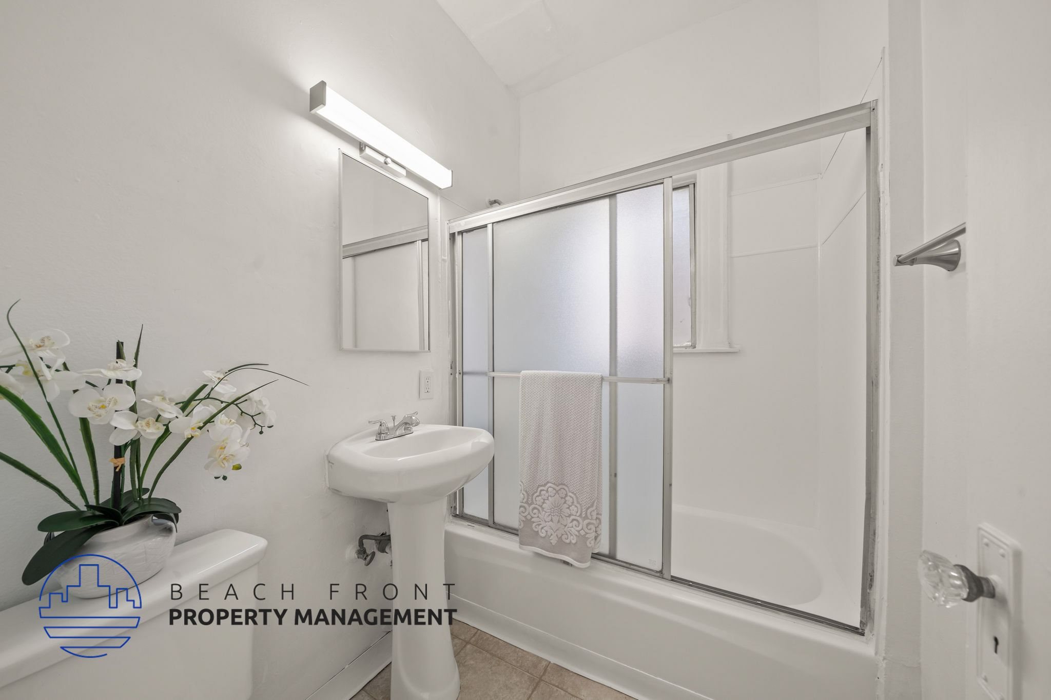 A white bathroom with a sink, mirror, and shower.