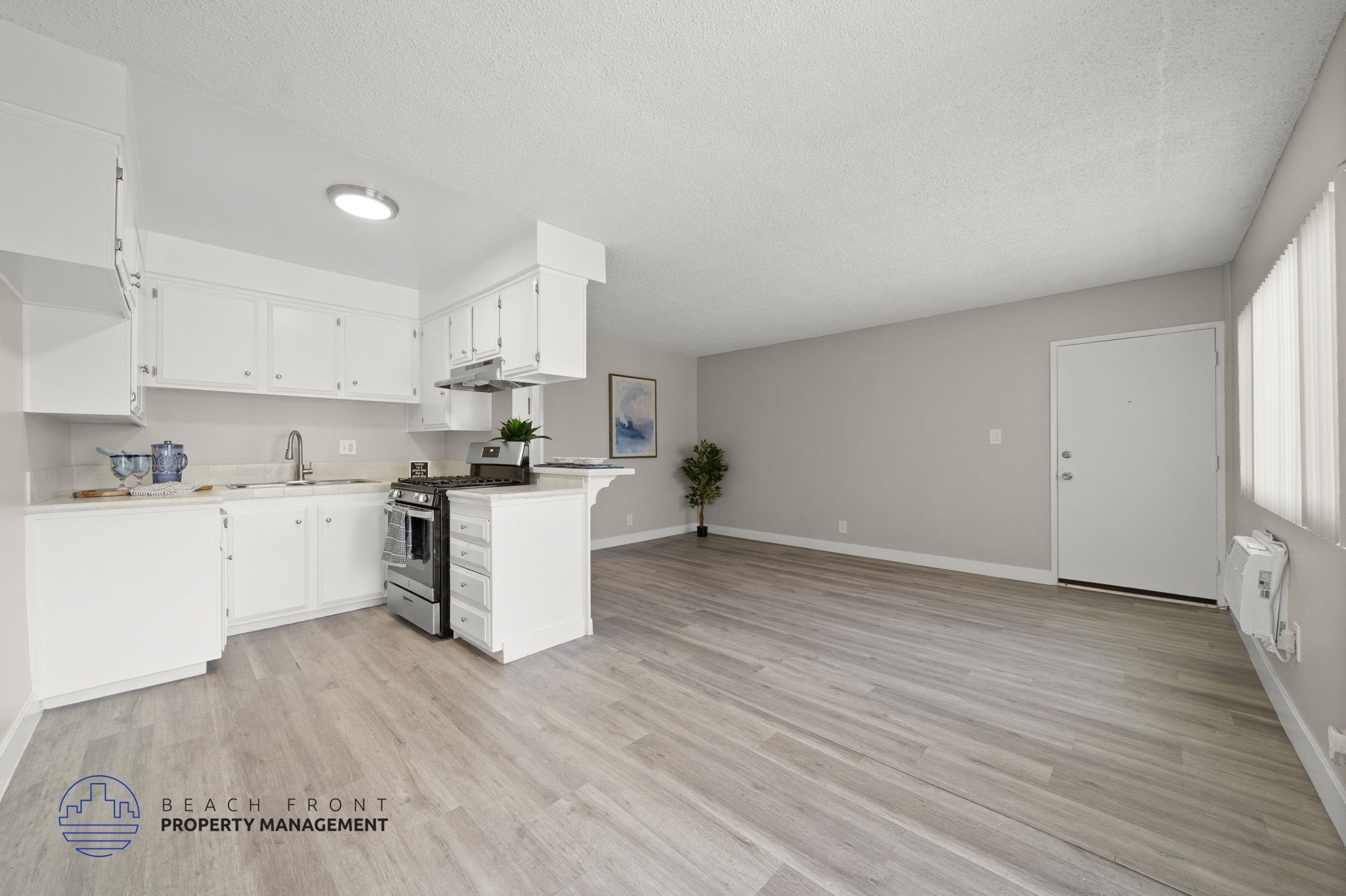A spacious kitchen with white cabinets and a wooden floor.