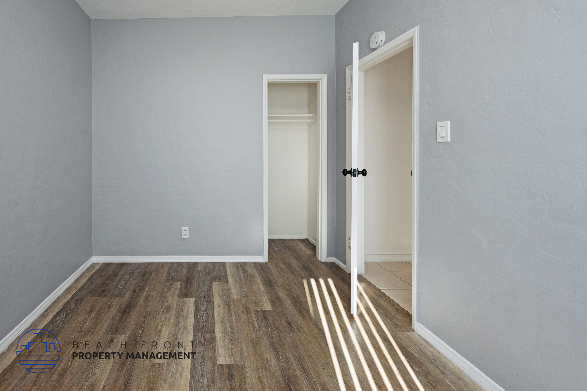A room with wooden flooring and two white doors.