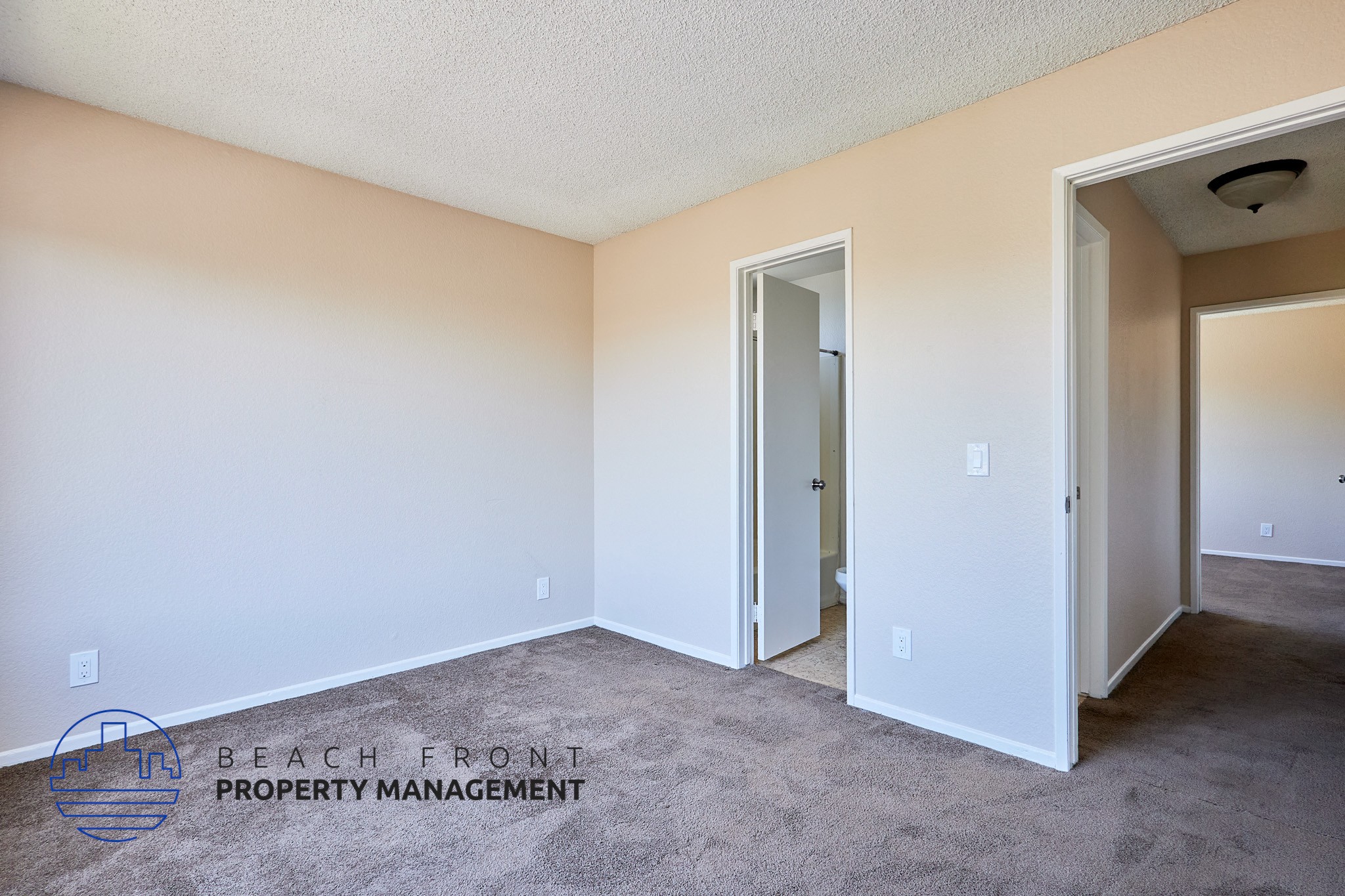 A room with a carpeted floor and two doors, one of which is open.