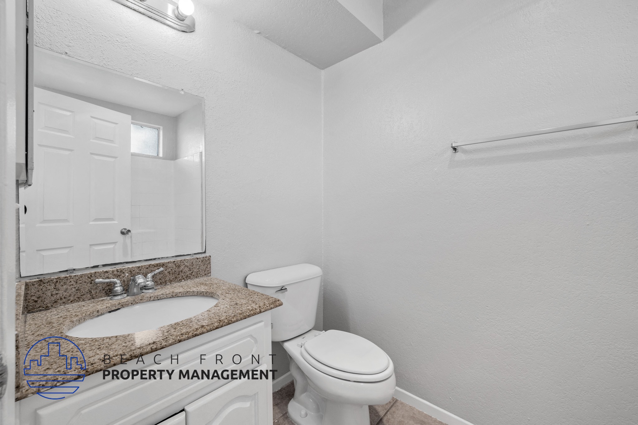 A bathroom with a toilet, sink, and mirror.