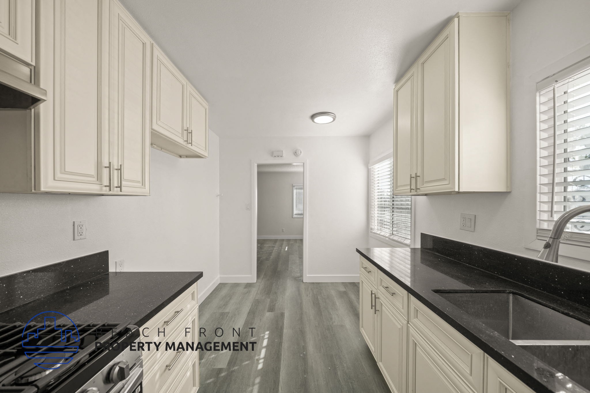 A kitchen with white cabinets and black countertops.