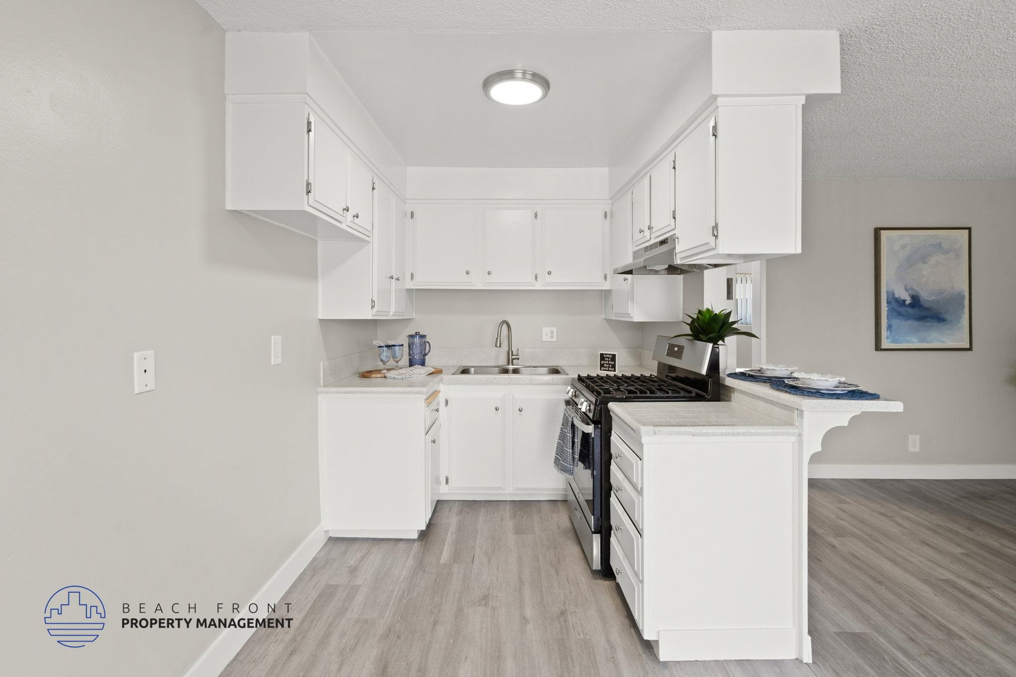 A kitchen with white cabinets and a wooden floor.