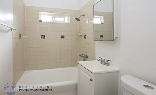 A bathroom with a white tub, sink, and toilet.