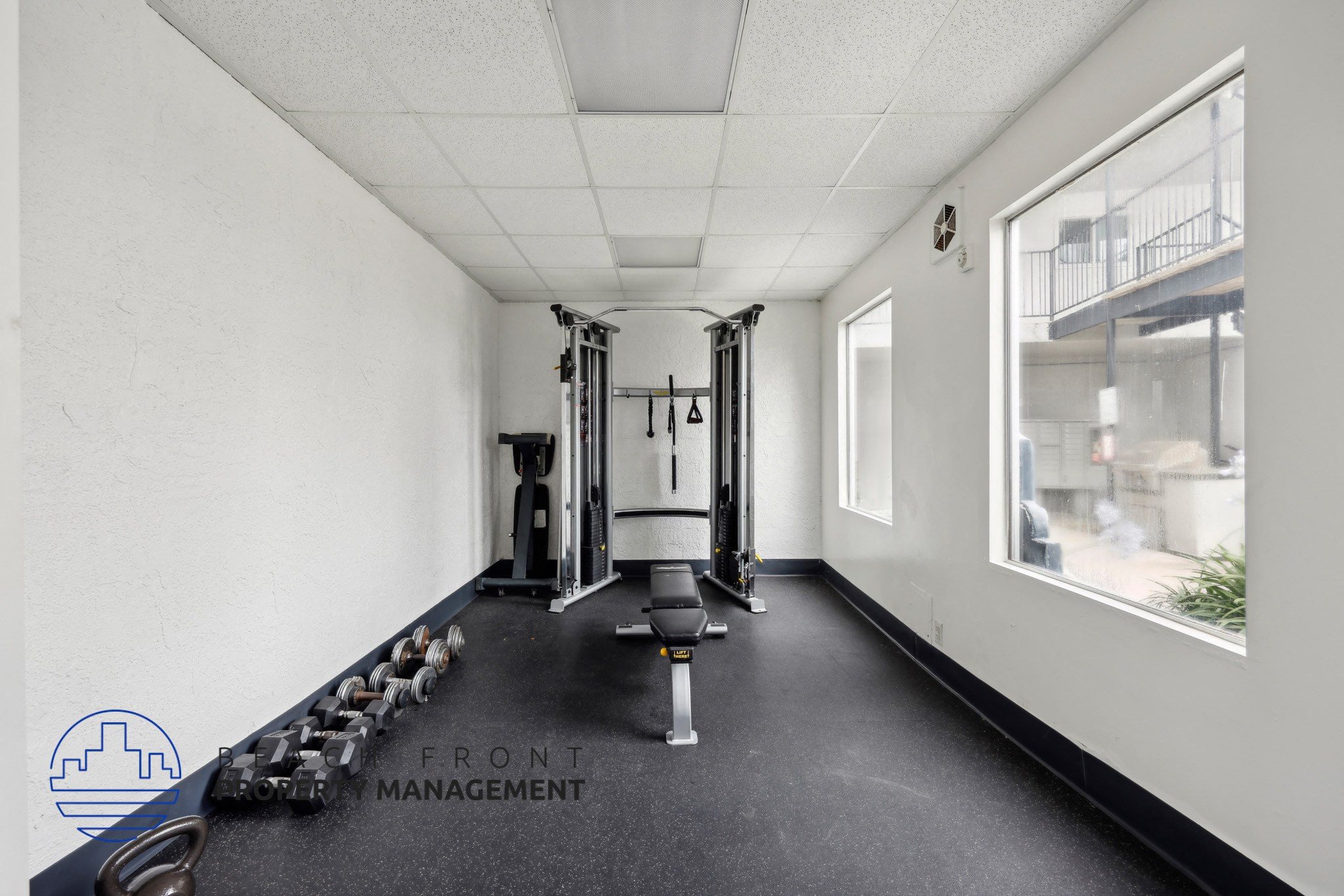 A gym with a row of dumbbells and a weight rack.