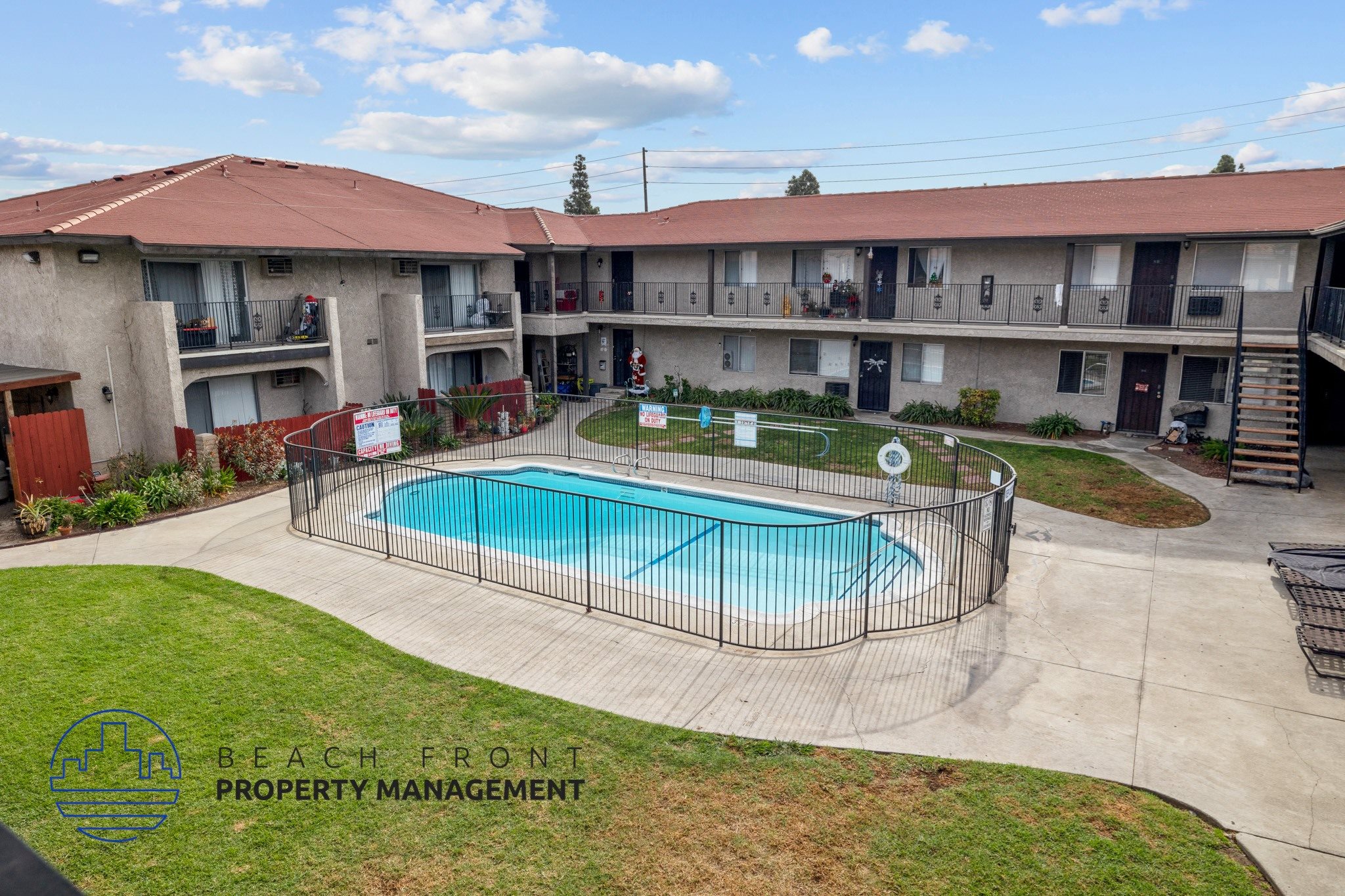 A swimming pool is surrounded by a fence in a courtyard.