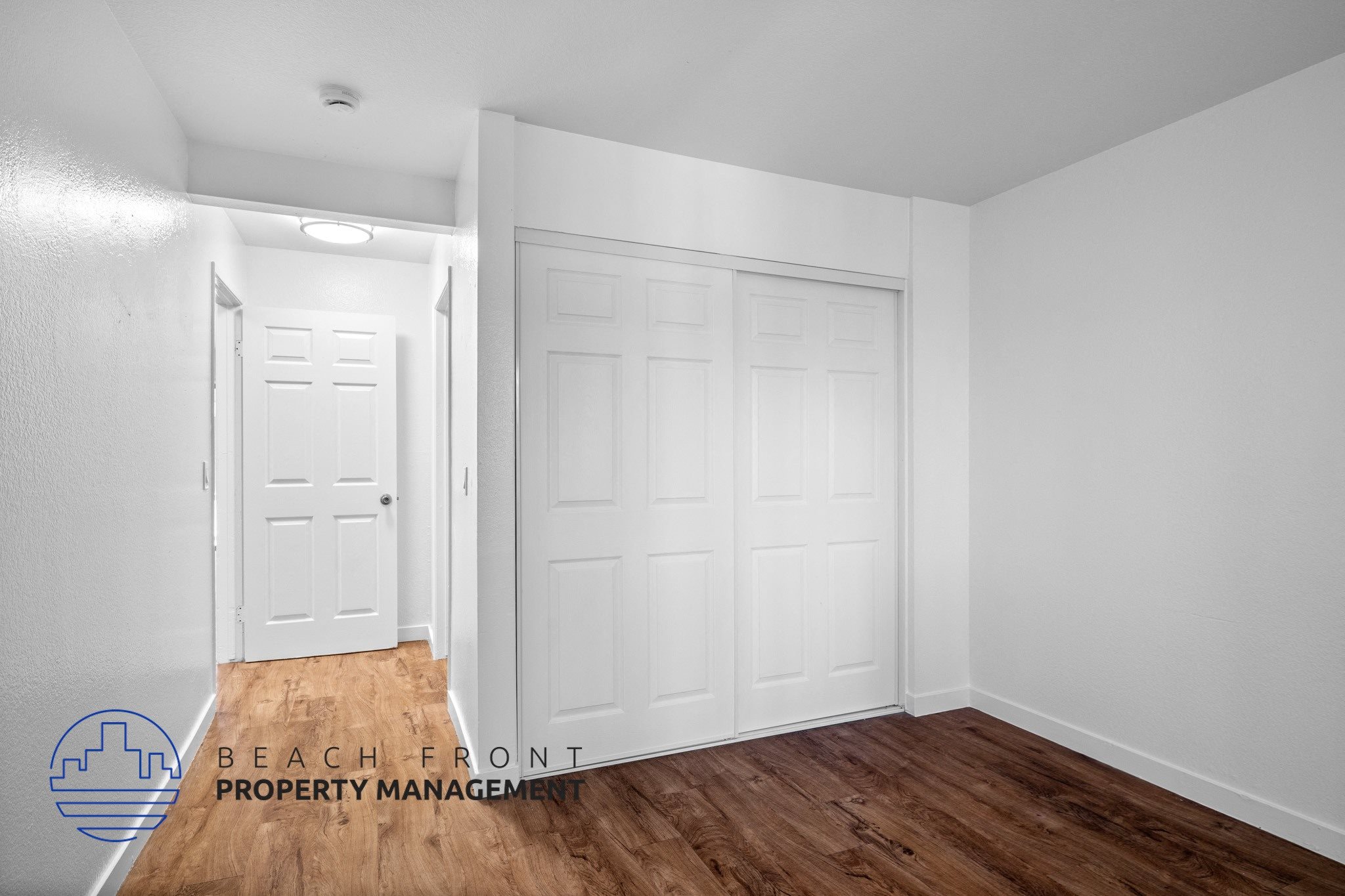 A room with two white doors and a logo for Beach Front Property Management.,A room with two white doors and a logo for Beach Front Property Management.