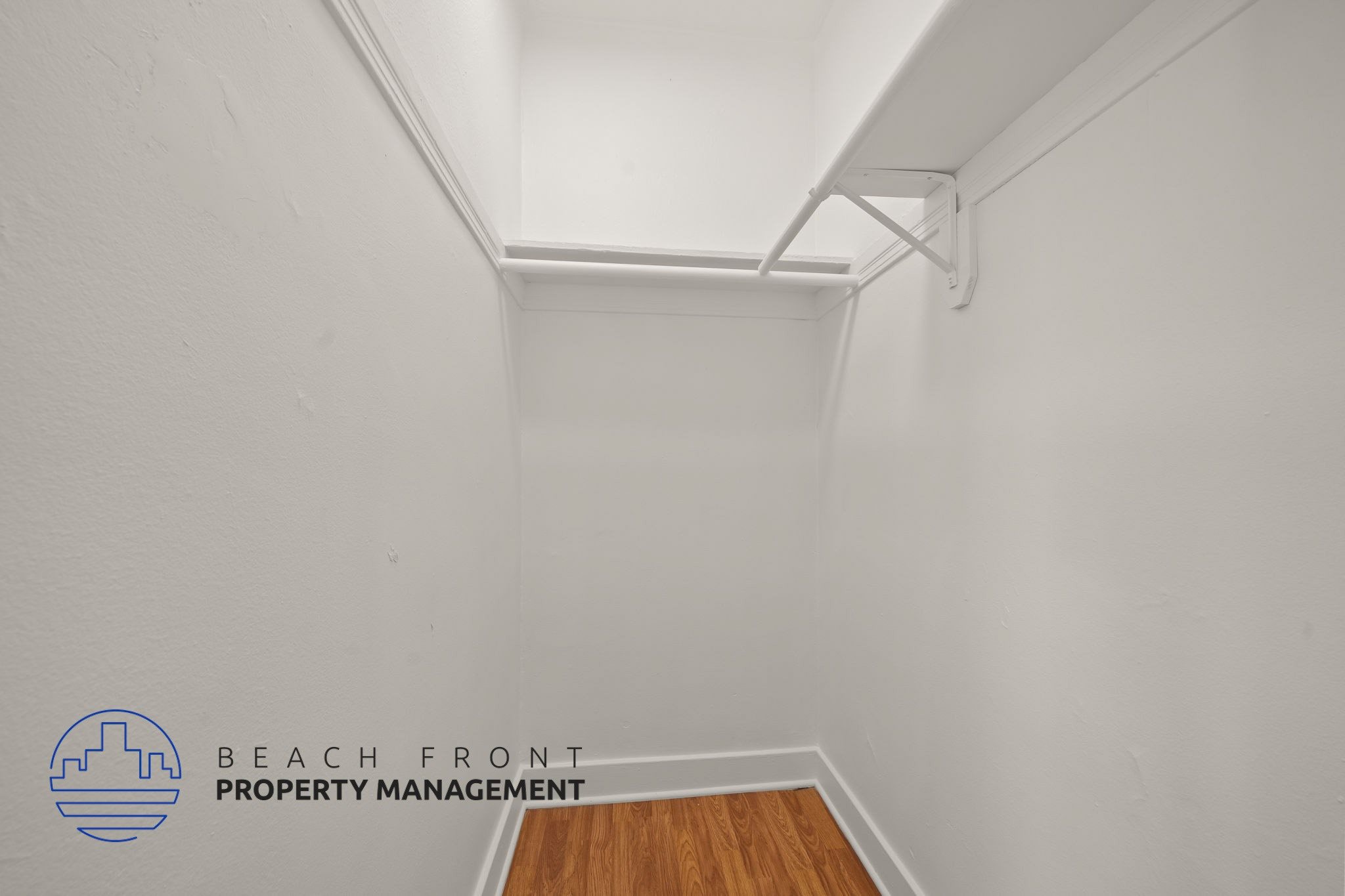 A white room with a wooden floor and a white ceiling with a beam.