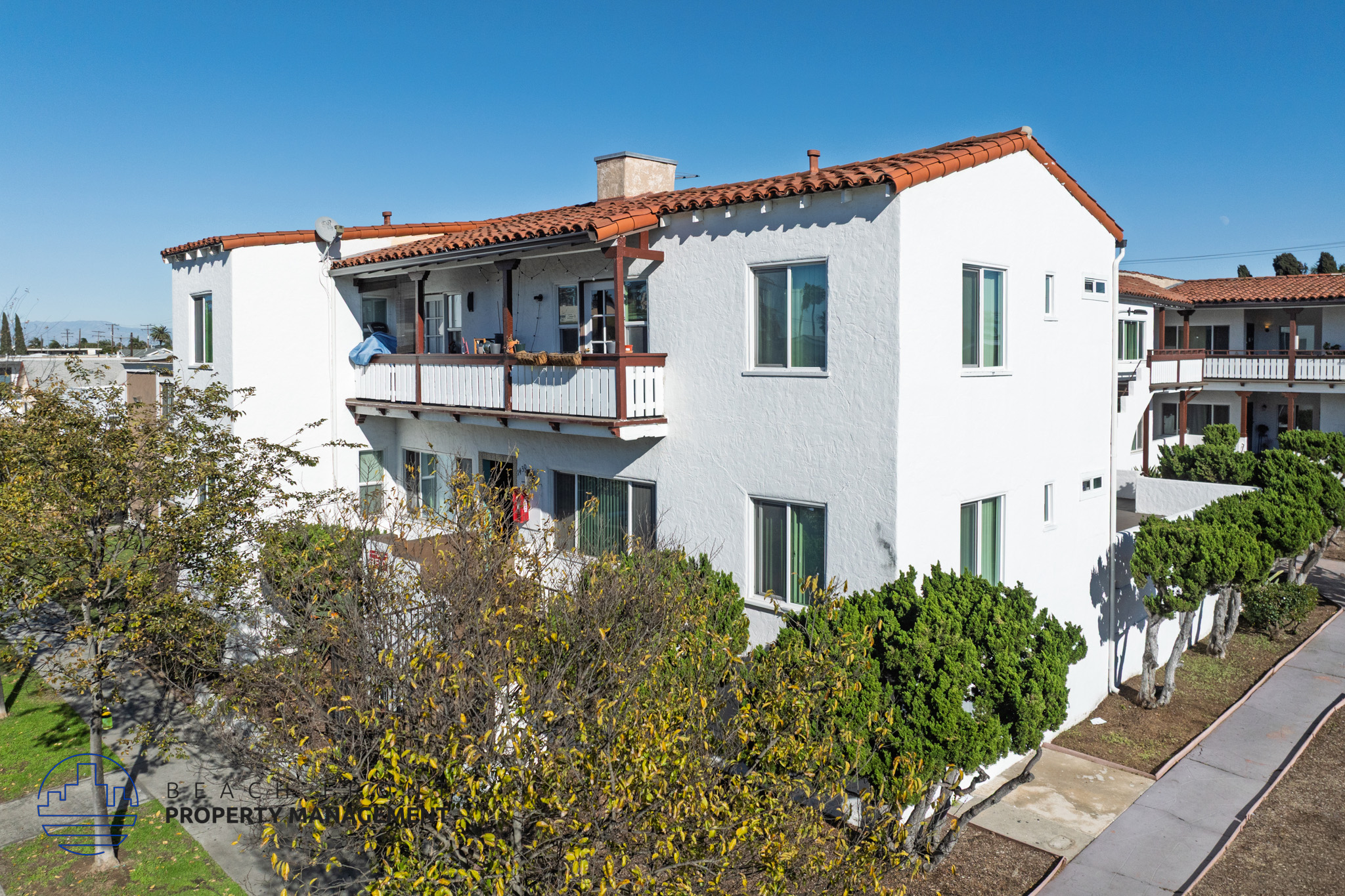 A white building with a red tile roof and a balcony.