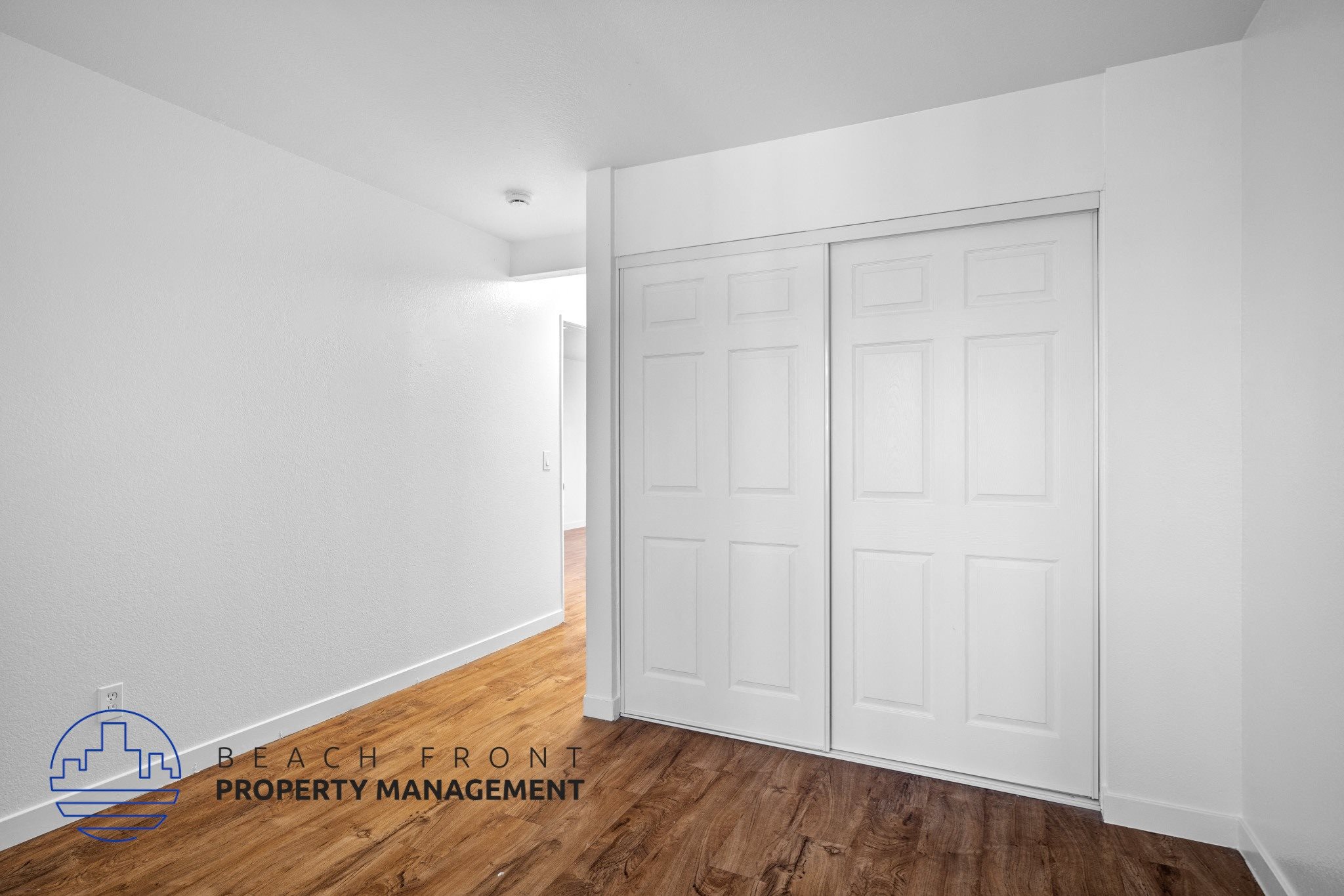 A white room with a wooden floor and a white door.,A white room with a wooden floor and a white door.