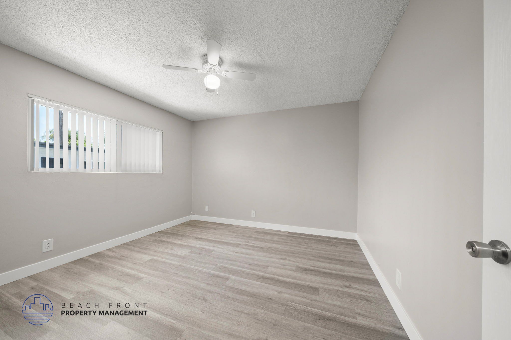 A room with a ceiling fan and a window with blinds.