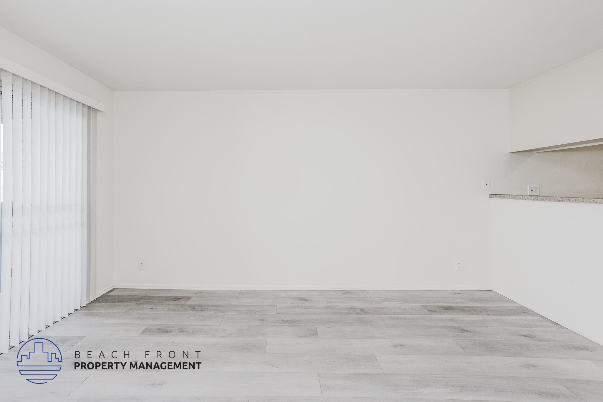 A spacious room with a wooden floor and white walls.