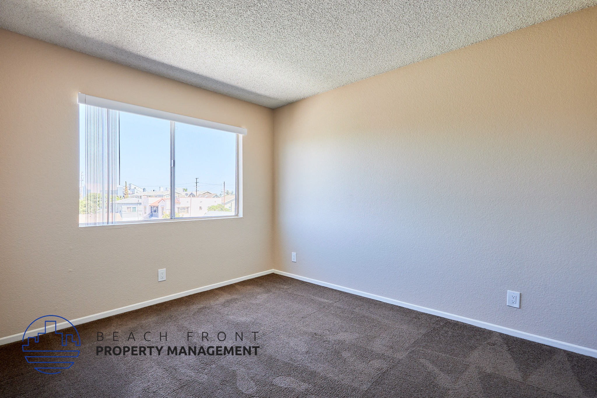 A room with a large window and a carpeted floor.
