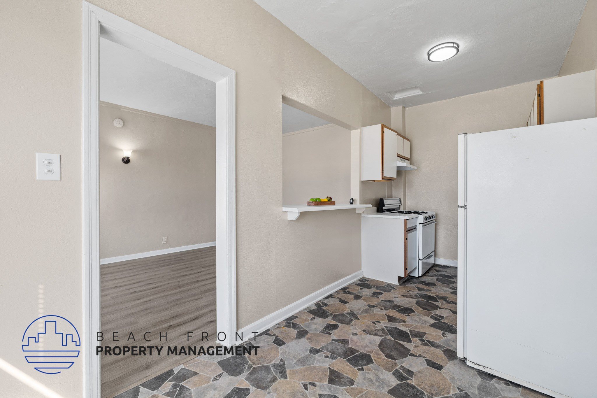 A kitchen with a white refrigerator and a stone floor.
