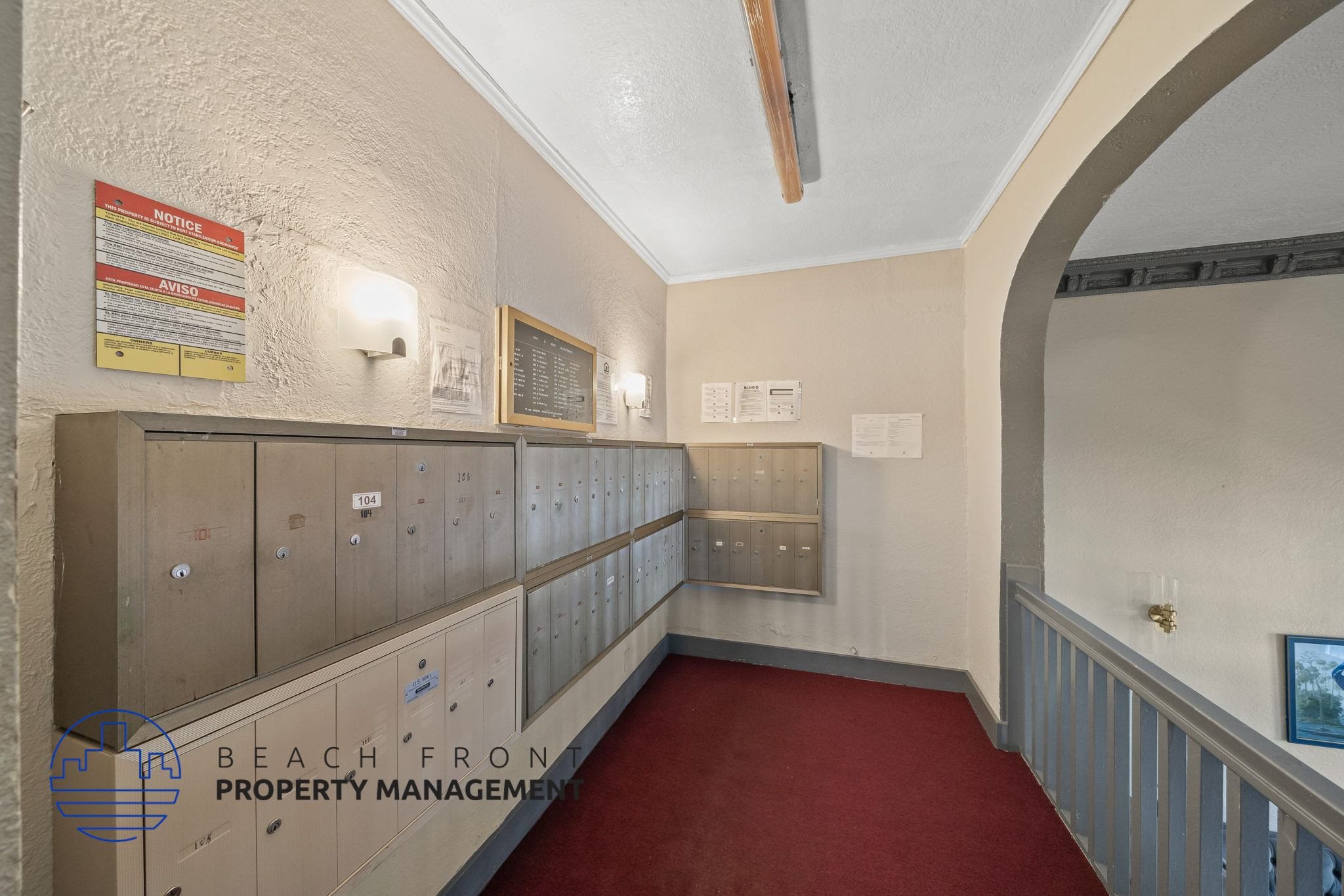 A long hallway with a red carpet and a sign that says Beach Front Property Management.